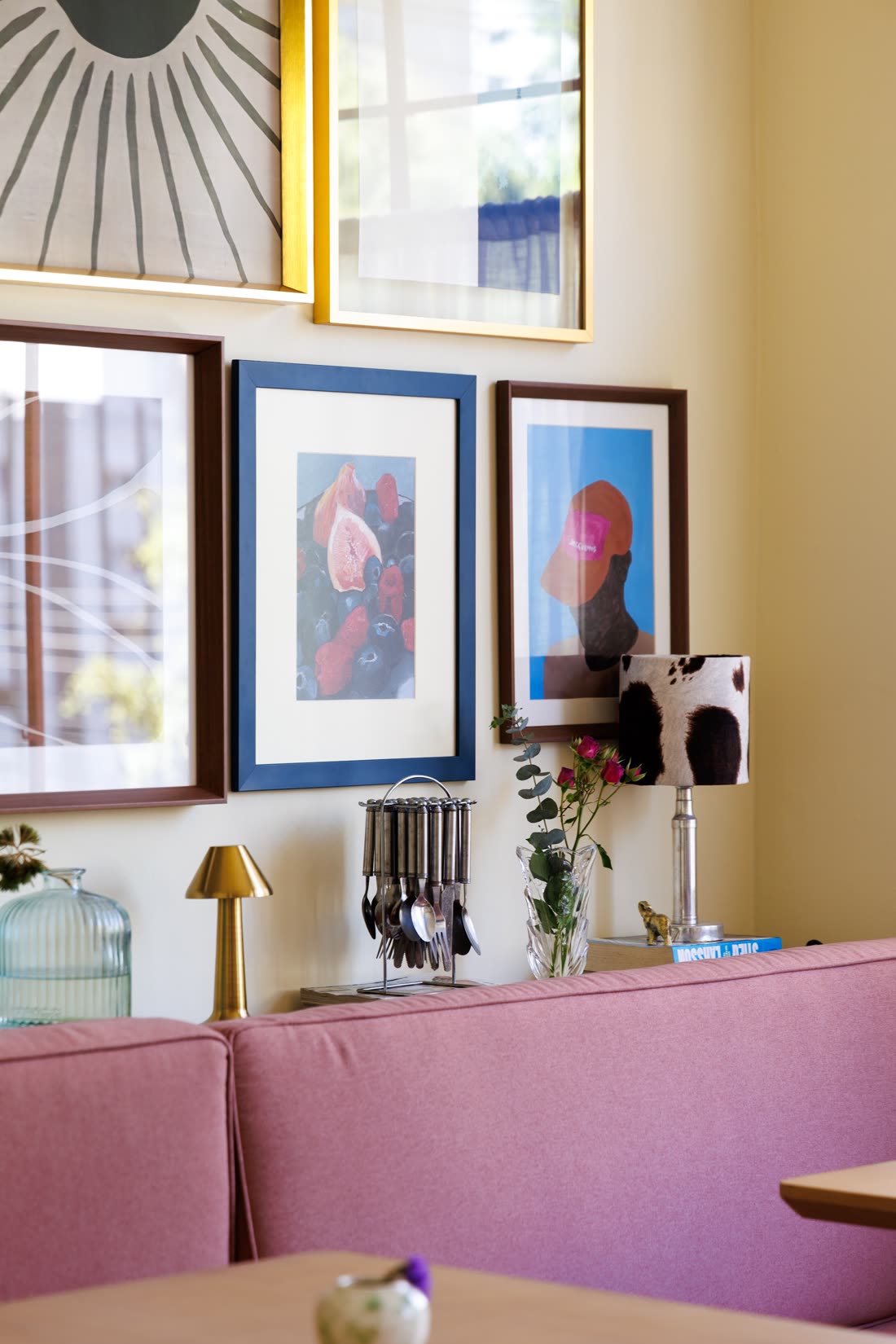 Parede-galeria com quadros, luminária e banco estofado