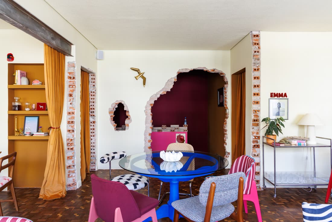 Mesa azul e cadeira rosa sob arco de tijolos com o Emma